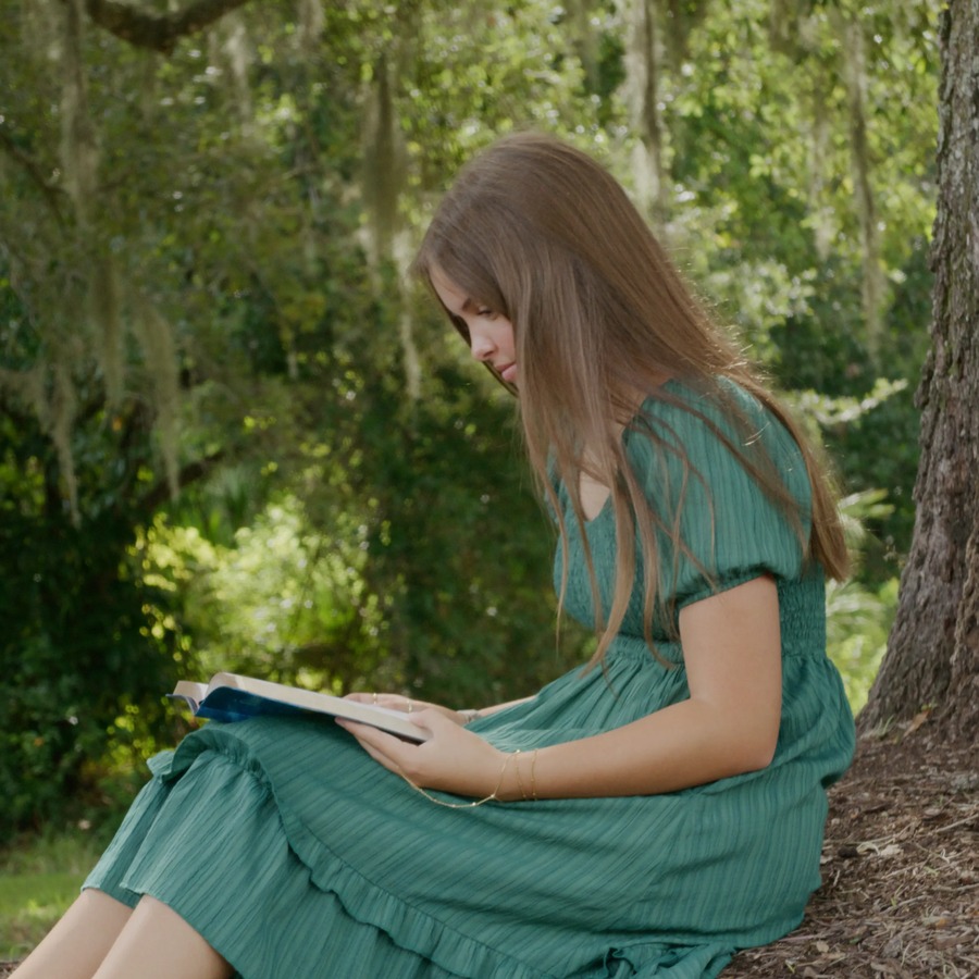 A young woman reading scriptures outdoors